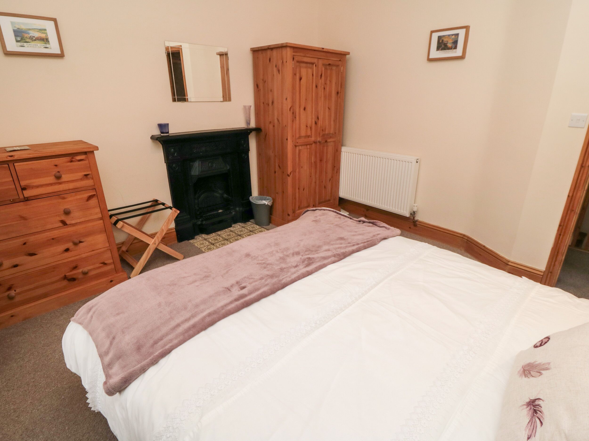 Un dormitorio con cama, cómoda, armario de madera, chimenea y radiador.