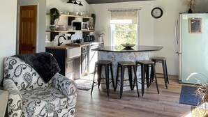 Una cocina moderna con comedor, que incluye un ventilador de techo, un refrigerador y una ventana con cortinas.