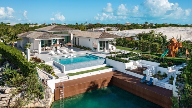 Une maison moderne dotée d’une piscine, d’un espace salon extérieur et d’une aire de jeux.