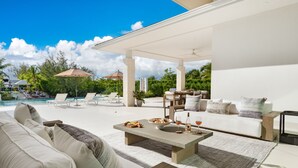 Un vaste espace de vie extérieur comprenant une piscine, des chaises longues, une table à manger et un canapé.