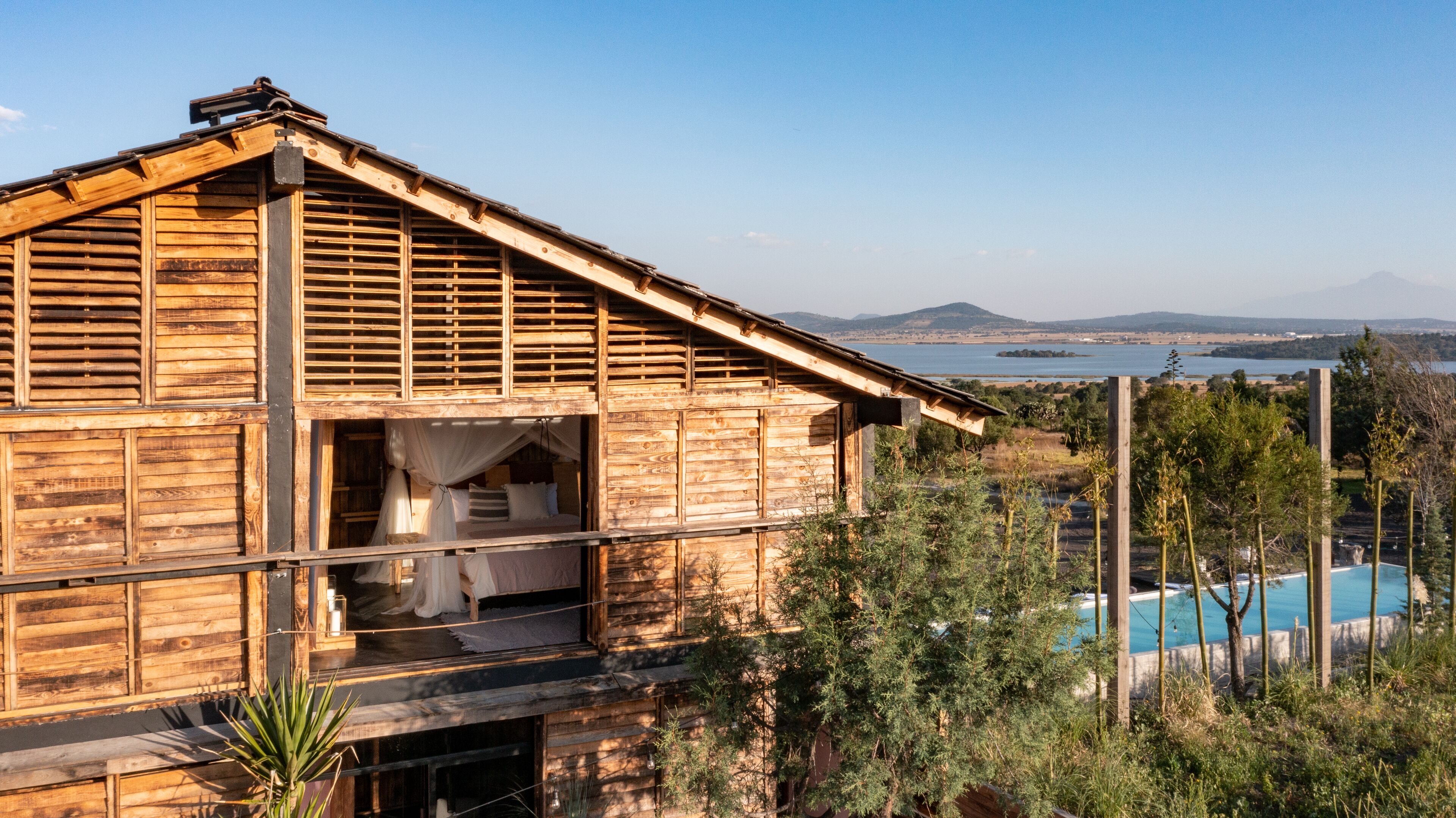Una cabaña de madera con balcón que da a una piscina y un lago.