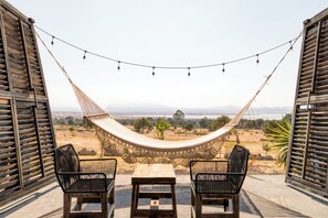Una hamaca con vista a un paisaje, dos sillas y una mesa.