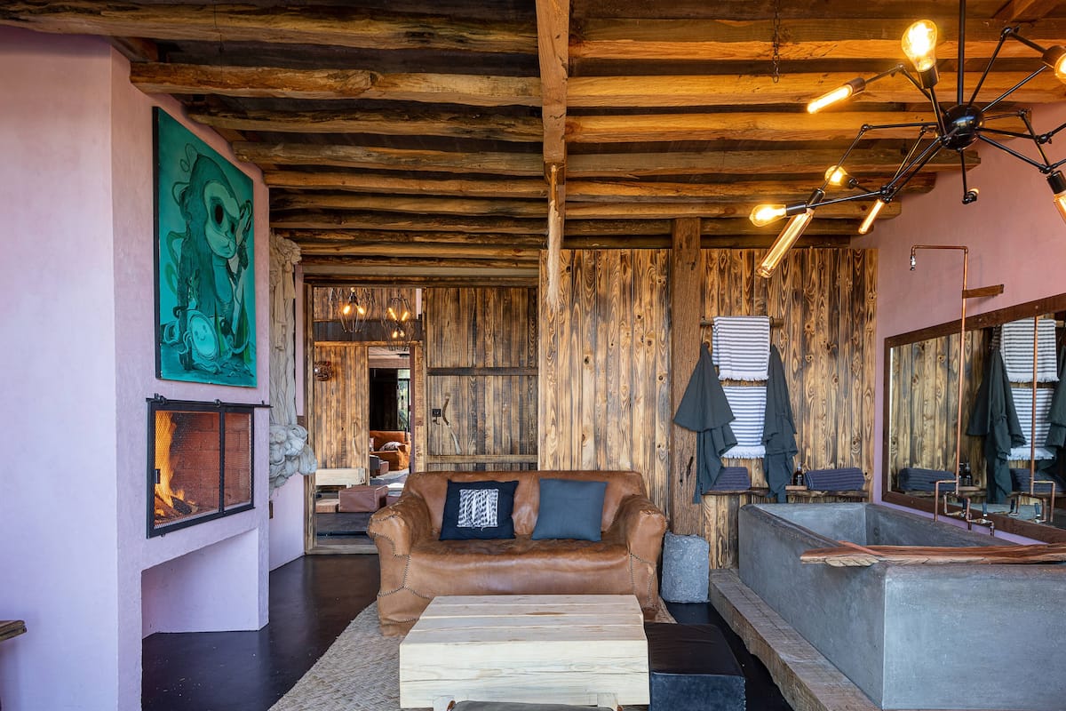 Um quarto acolhedor com teto de madeira, sofá de couro, lareira e um espelho grande.