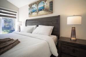 A bedroom with a bed, a nightstand, a lamp, and a painting on the wall.