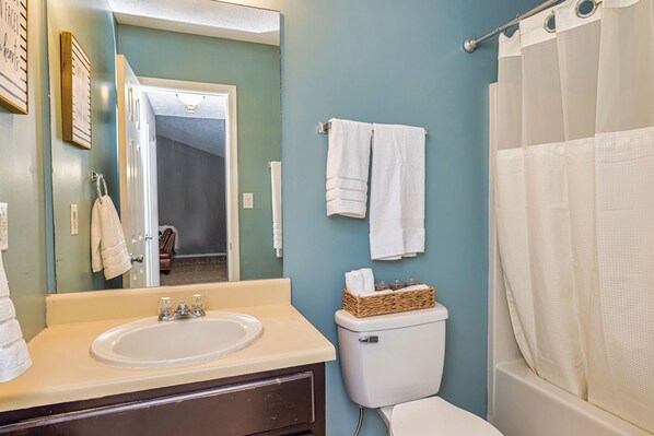 A bathroom with a sink, mirror, toilet, and shower curtain.