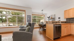 Une cuisine moderne avec des meubles en bois, un lave-vaisselle encastré et un coin repas comprenant une table et des chaises.