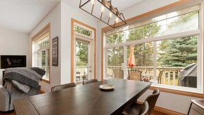 Un espace repas comprenant une grande table, des chaises et une vue sur l’extérieur.