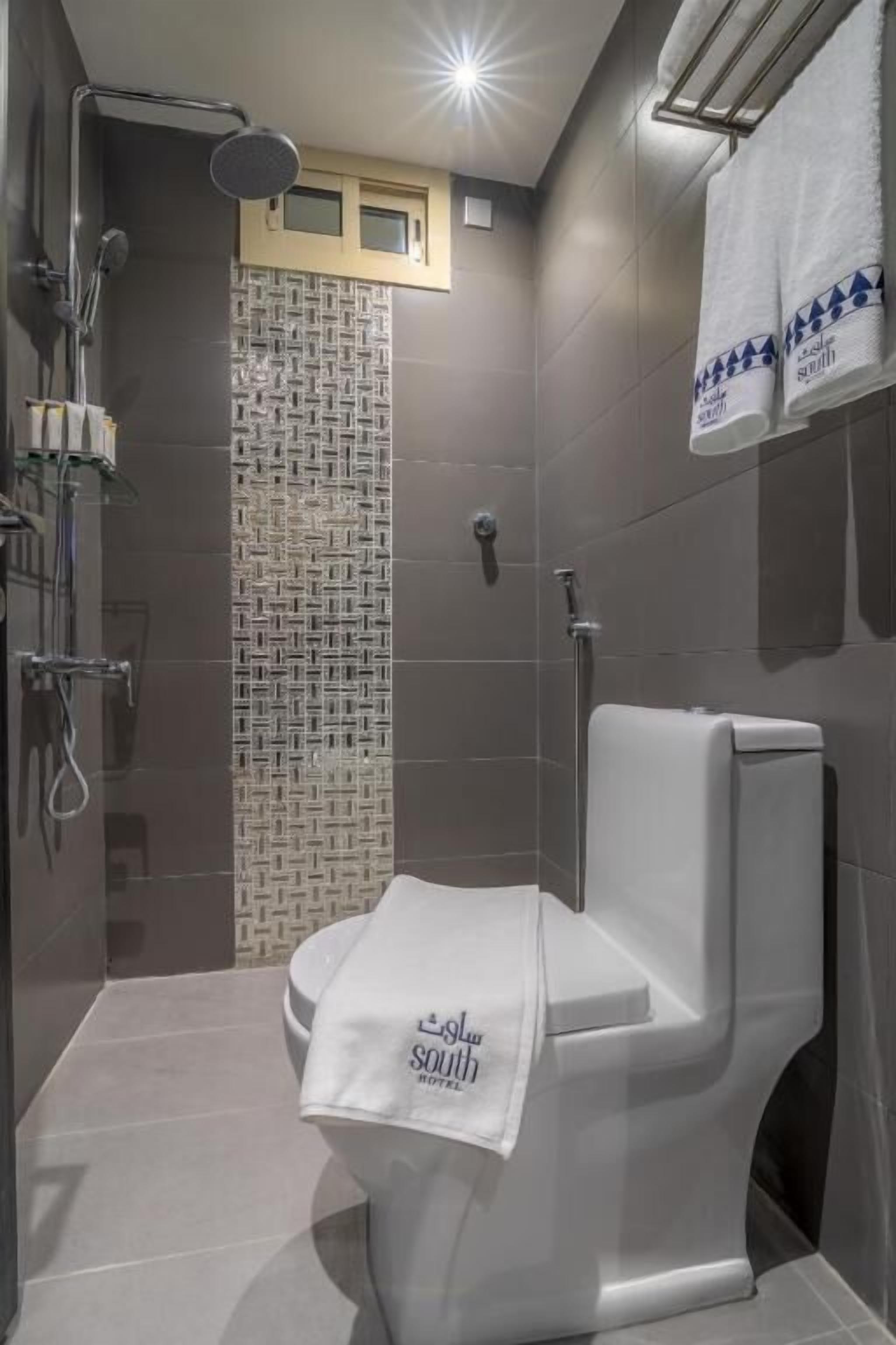 Un baño moderno con ducha, inodoro y pared con diseño.
