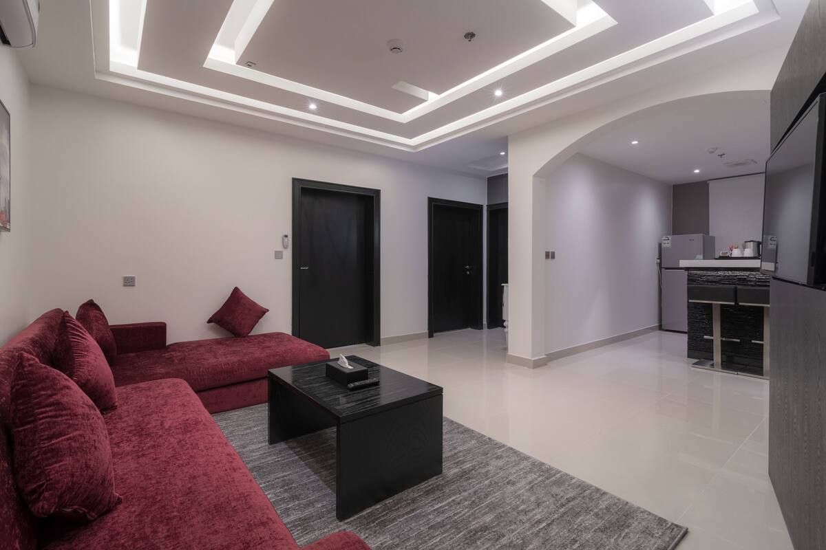 A modern living room with a red sofa, black coffee table, and recessed ceiling lighting.