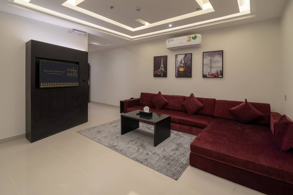 A modern living room with a red sofa, a black coffee table, and a mounted TV.