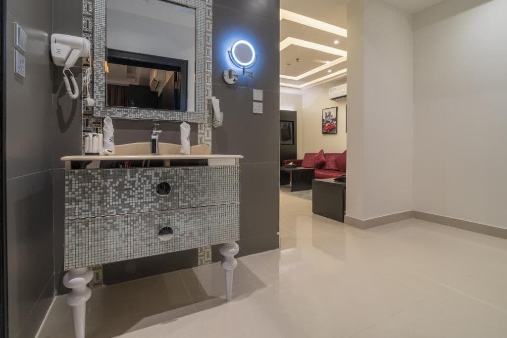 A modern bathroom with a tiled vanity, a mirror, a hairdryer, and a ring light.