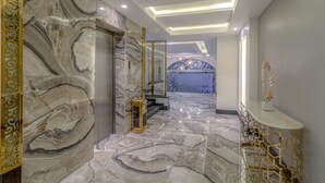 Un interior moderno con suelo de mármol, un revestimiento decorativo y una zona de estar con diseño geométrico.