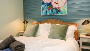 A neatly made bed with a blue quilt, two pillows, and a folded towel.