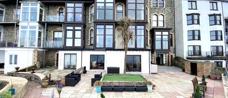 A townhouse with a courtyard featuring outdoor seating, a palm tree, and potted plants.