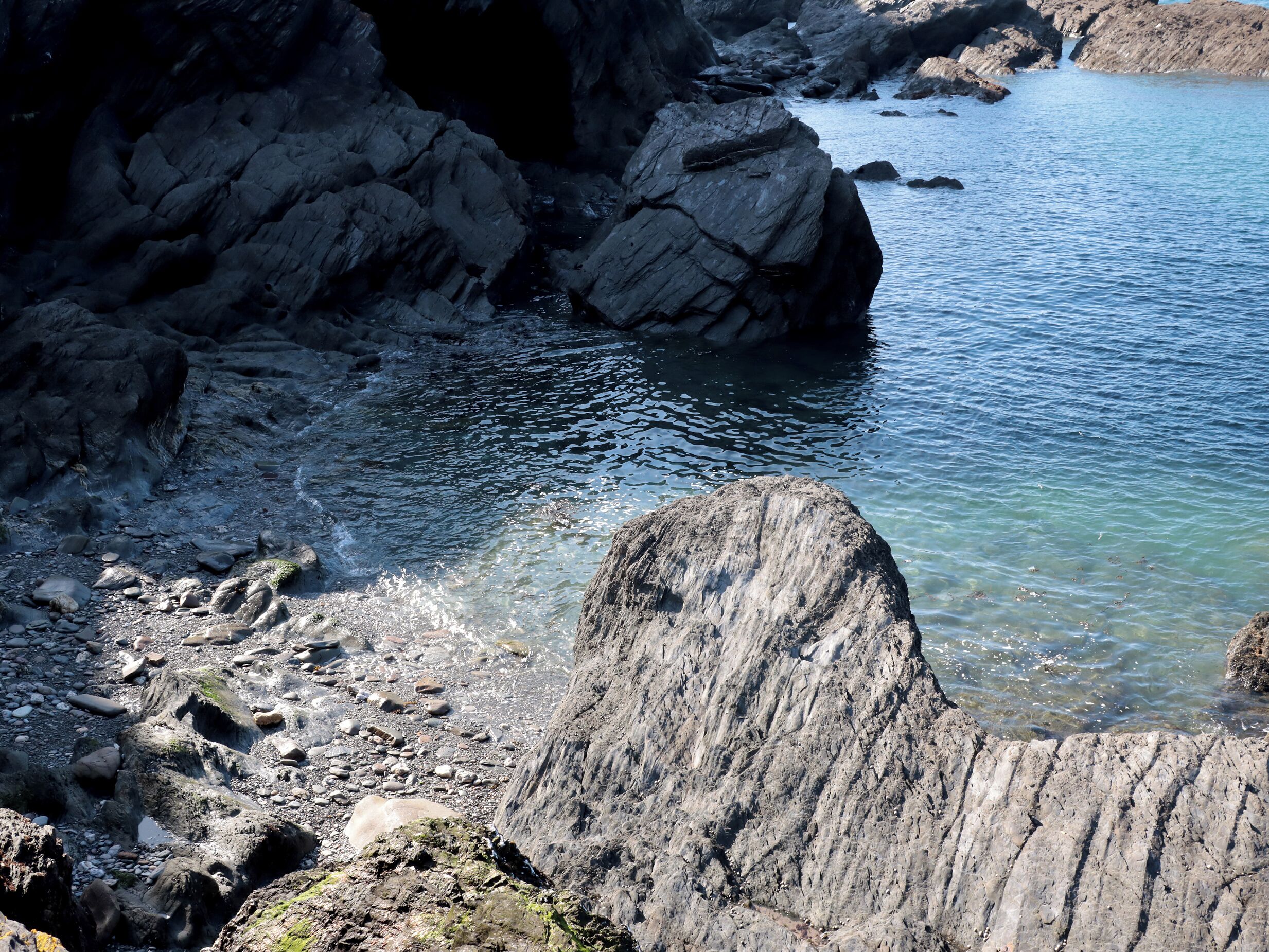 A rocky shoreline with clear water and large boulders.