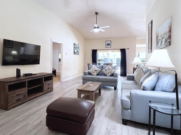A living room with a flat-screen TV, a ceiling fan, and a sofa with decorative pillows. - MEGA VALUE! Serenity By The Pool! Close 2 Disney! 1445 (Clermont)