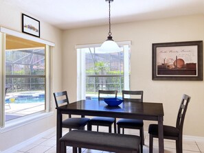 A dining area with a table, chairs, and a hanging light fixture. - MEGA VALUE! Serenity By The Pool! Close 2 Disney! 1445 (Clermont)