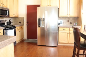 Una cocina con armarios de madera, un refrigerador de acero inoxidable, un microondas, una estufa y una cafetera.