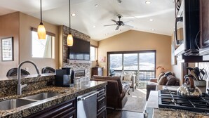 Una cocina con encimeras de granito, electrodomésticos de acero inoxidable y un amplio ventanal con vistas a la montaña.