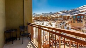 A balcony with a view of a snow-covered mountain town, wooden railings, and a small table with a chair. - Grand Summit Hotel | Great Ski Location! Luxury and Comfort (Park City)
