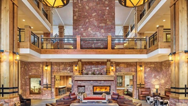 A spacious lobby with a stone fireplace, wooden furniture, and a balcony with railings. - Grand Summit Hotel | Great Ski Location! Luxury and Comfort (Park City)