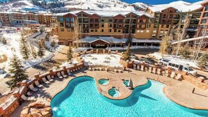 A resort with a pool area, multiple buildings, and a snowy mountain backdrop. - Grand Summit Hotel | Great Ski Location! Luxury and Comfort (Park City)