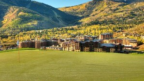 A resort with multiple buildings, a golf course, and a mountainous backdrop. - The Grand Summit Hotel in the Canyons Village - Close to Golf - Pool, Gym, Spa, More! (Park City)