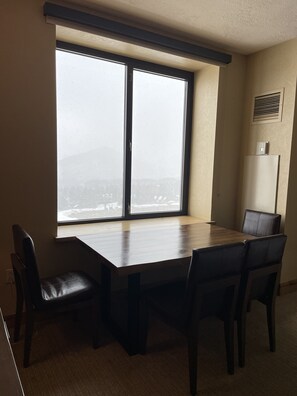 Comedor con un amplio ventanal, una mesa de madera y cuatro sillas.