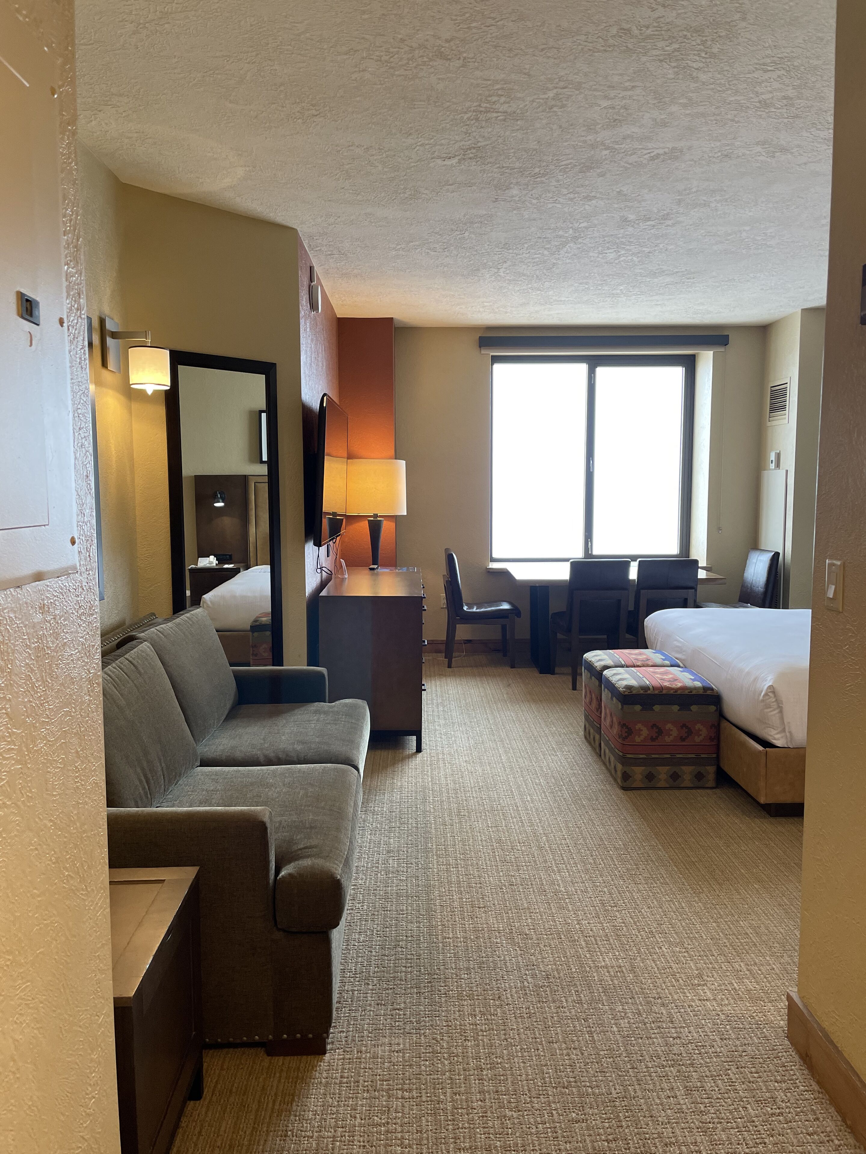 Une chambre d’hôtel avec un canapé, un bureau, une chaise, un lit et une fenêtre.
