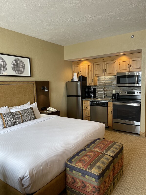 Una habitación de hotel con una cama, una kitchenette pequeña y un baño.