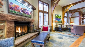 A spacious living room with a stone fireplace, comfortable seating, and large windows.