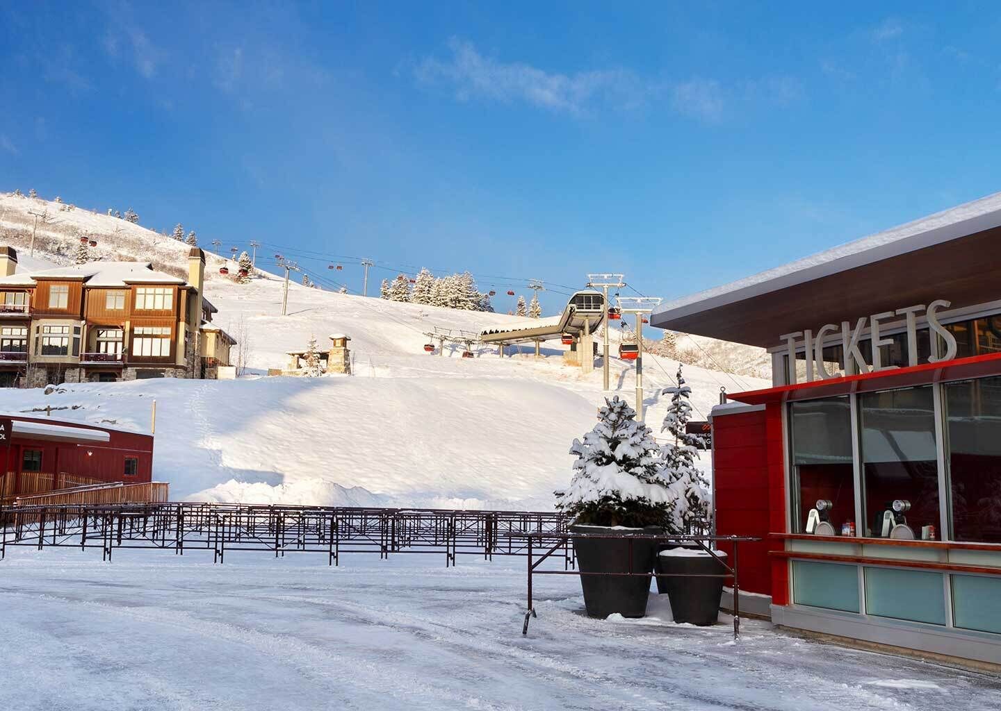 A snow-covered ski resort with a ticket office and a ski lift in the background.