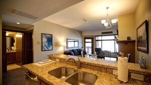 A modern kitchen with granite countertops, stainless steel sinks, and a chandelier.