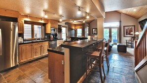 A spacious kitchen with a large island, wooden cabinets, and a stainless steel refrigerator. - Beautiful Historic Town Home, Walk to Main St - Large Deck w/ Mountain Views and Private Hot Tub! (Park City)
