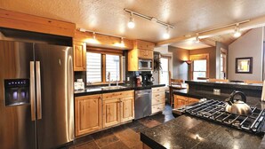 A modern kitchen with stainless steel appliances, wooden cabinets, and a granite countertop. - Beautiful Historic Town Home, Walk to Main St - Large Deck w/ Mountain Views and Private Hot Tub! (Park City)