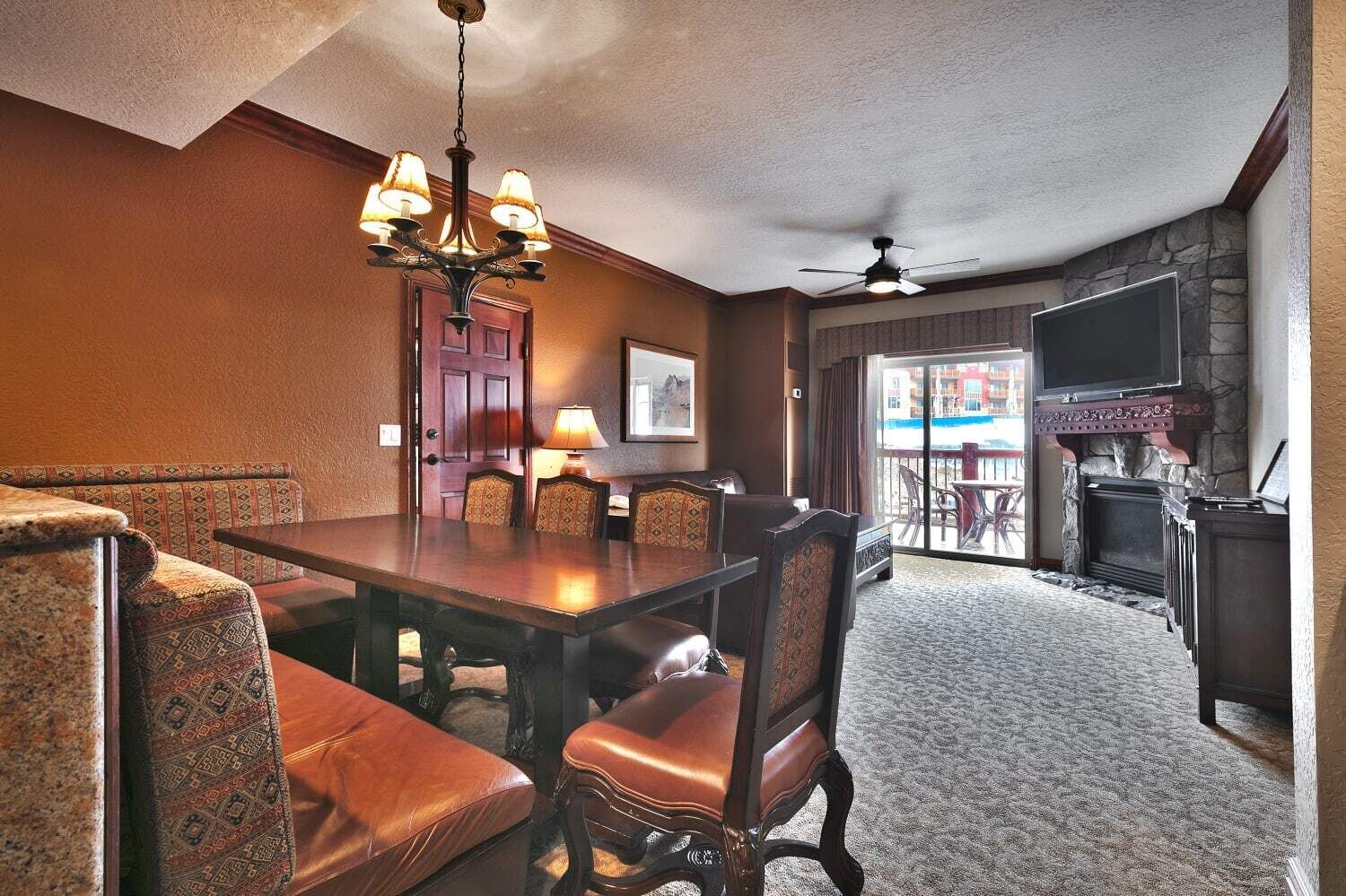 A dining area with a wooden table and chairs, a chandelier, and a fireplace.