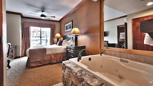 Une chambre d’hôtel dotée d’un grand lit, d’un coin salon séparé, d’une salle de bain avec baignoire et d’un grand miroir.