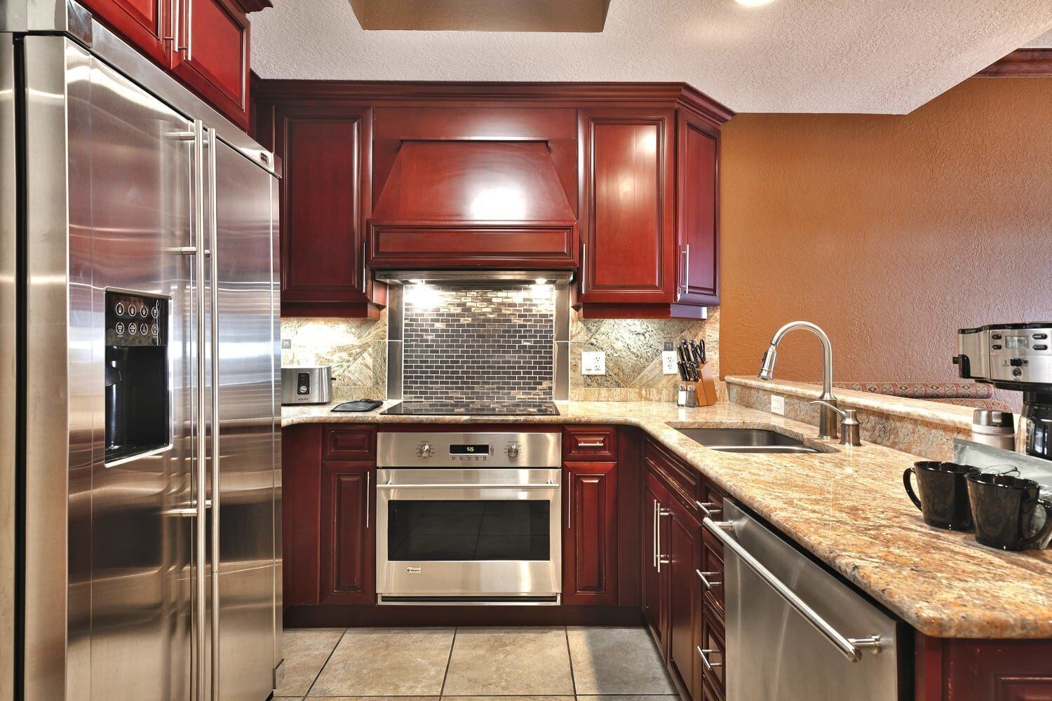 A modern kitchen with stainless steel appliances, dark wooden cabinets, and a granite countertop.