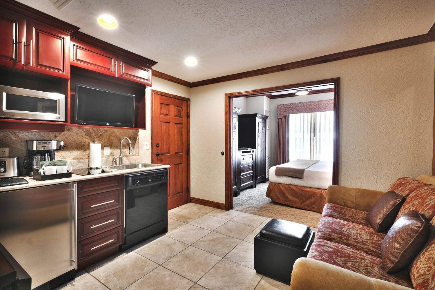 A compact living space with a kitchenette, a sofa, and a bed.