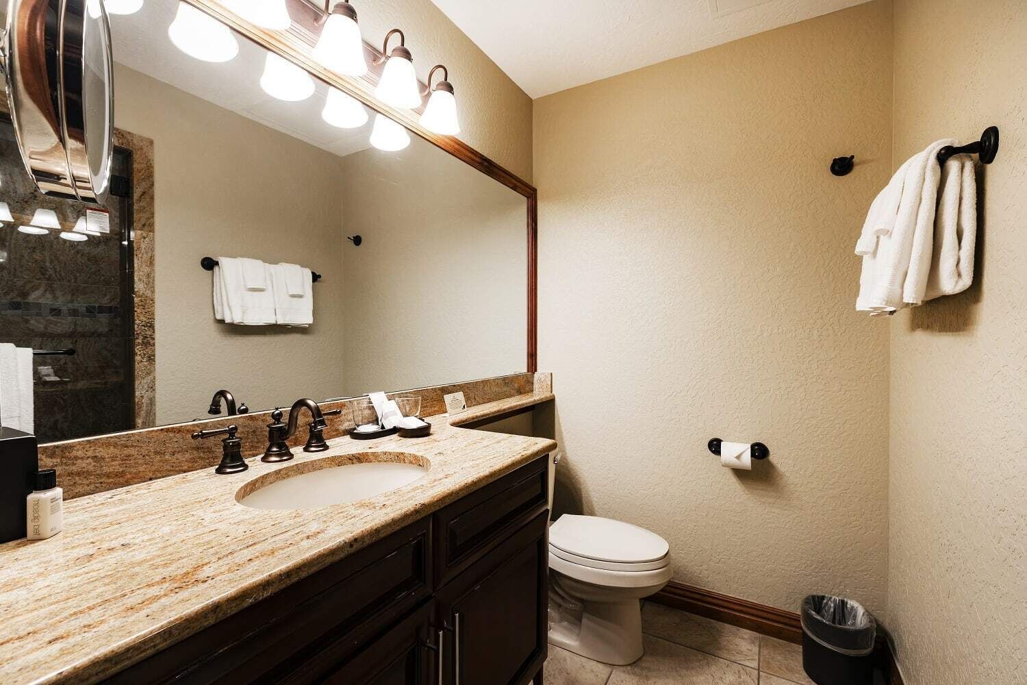 A bathroom with a marble sink, a large mirror, and a toilet.