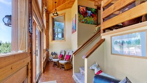 A wooden interior with a staircase, a sofa, and a chair. - Multiple Decks + Solarium Sitting Room, Office Space & Dog Friendly! (Woodland Park)