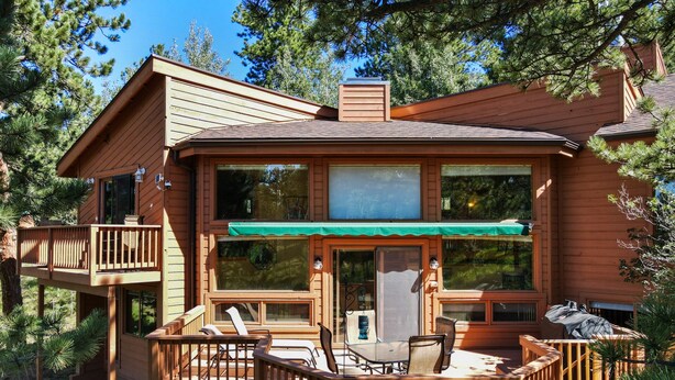 A wooden cabin with a deck, outdoor seating, and large windows. - Multiple Decks + Solarium Sitting Room, Office Space & Dog Friendly! (Woodland Park)