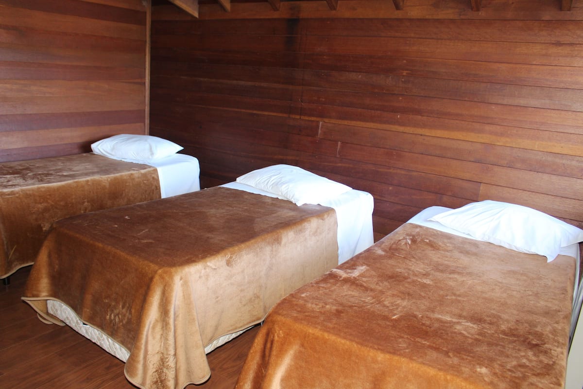 Una habitación con tres camas, cada una con una colcha marrón y almohadas blancas.