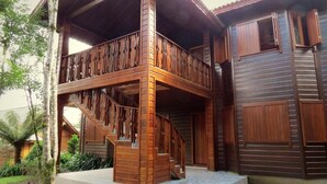 A two-story wooden house with a balcony and a staircase. - Pousada Floresta Negra (Canela)