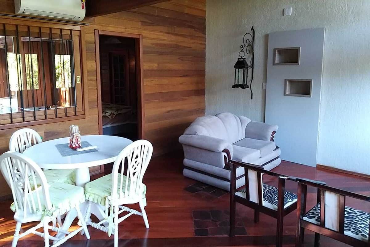 Una habitación con una mesa redonda y sillas blancas, un sofá gris y un banco de madera.