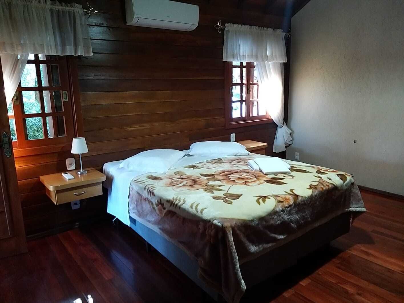 Une chambre aux murs lambrés, avec un lit, des tables de chevet et une fenêtre avec des rideaux.