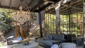 A modern outdoor seating area with a cushioned sofa, round ottomans, and a bench. - Cabin Forest Retreat (Monte rio)