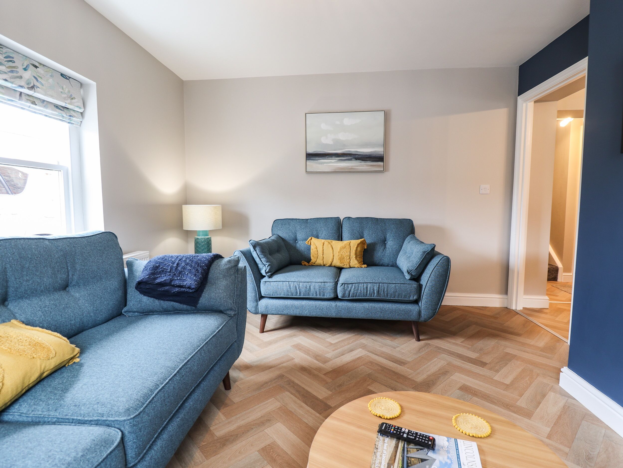 A living room with two blue sofas, a wooden coffee table, and a lamp.