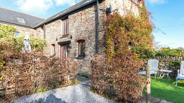 A stone building with a gravel driveway and a garden area with chairs. - 3 bedroom accommodation in Stoke Fleming, near Dartmouth (Stoke Fleming, near Dartmouth)