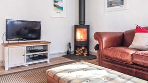 A living room with a television, a sofa, a fireplace, and two framed pictures on the wall. - 3 bedroom accommodation in Stoke Fleming, near Dartmouth (Stoke Fleming, near Dartmouth)